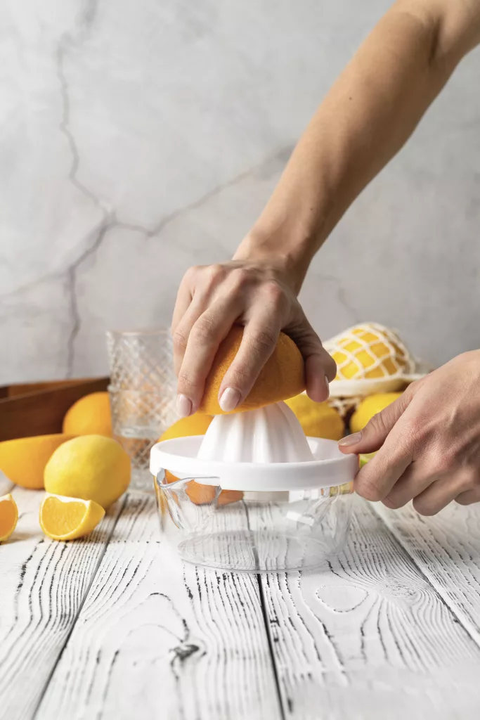 a person squeezing an orange into a juicer