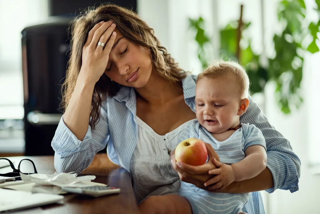 a woman holding a baby and a fruit
