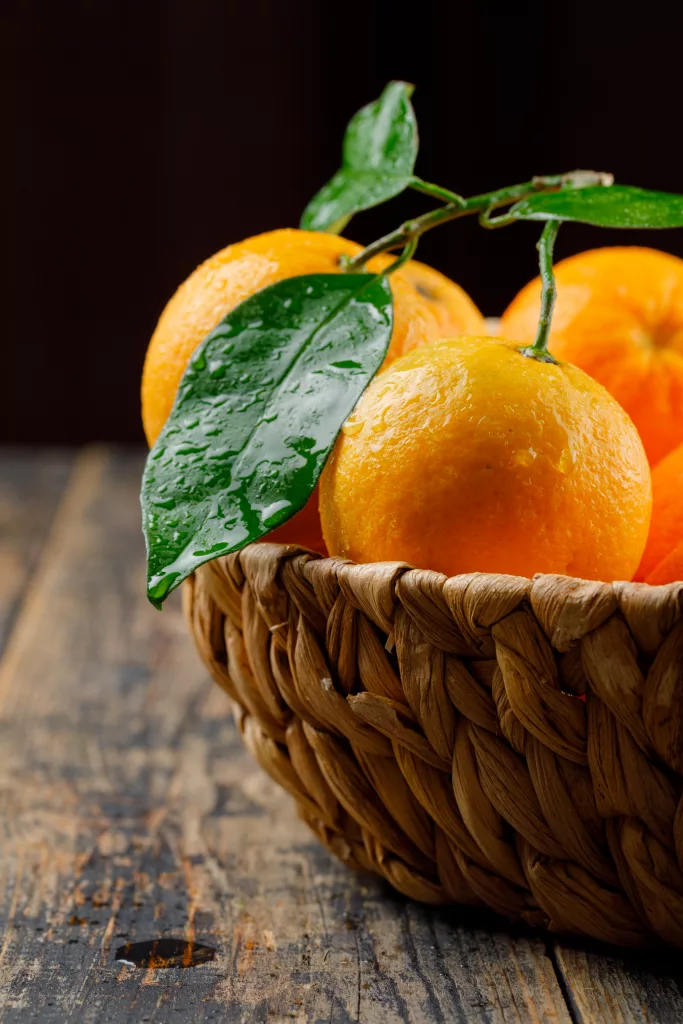 a basket of oranges with leaves