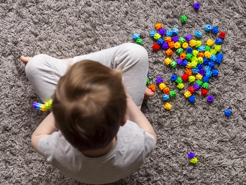 a child sitting on the floor with many colorful blocks
