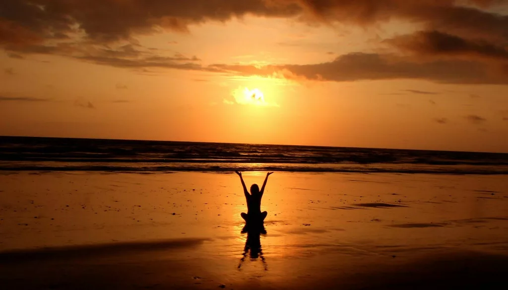 Peaceful meditation silhouette at sunset on a serene beach.