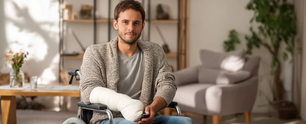 jeune homme sur un fauteuil roulant avec bras cassé