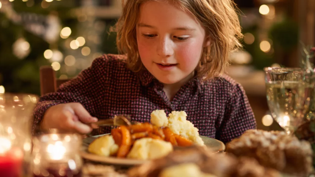 Enfant mangeant calmement un repas de Noël adapté , assis à table dans une ambiance chaleureuse et lumineuse