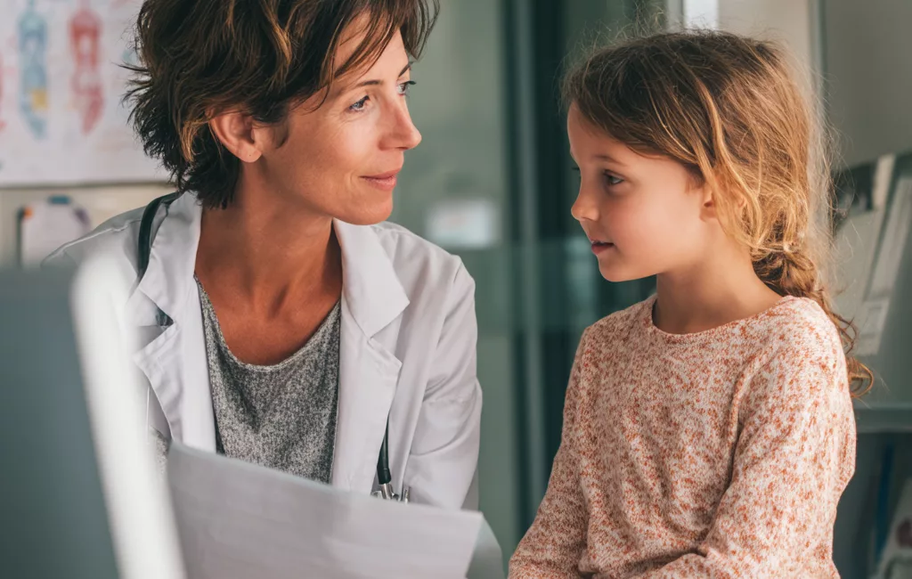 Médecin avec dans les mains le certificat médical MDPH à une petite fille lors d'une consultation