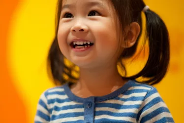 Fillette souriante utilisant une tablette CAA - la technologie aide les enfants autistes à communiquer