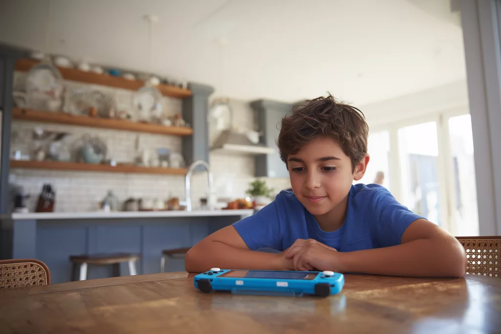 Jeune garçon concentré sur une tablette de communication alternative CAA pour enfant autiste non verbal