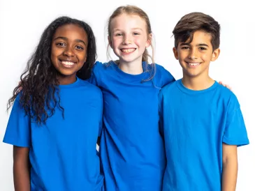 2 Avril Trois enfants souriants portant des t-shirts bleus pour la Journée mondiale de sensibilisation à l'autisme