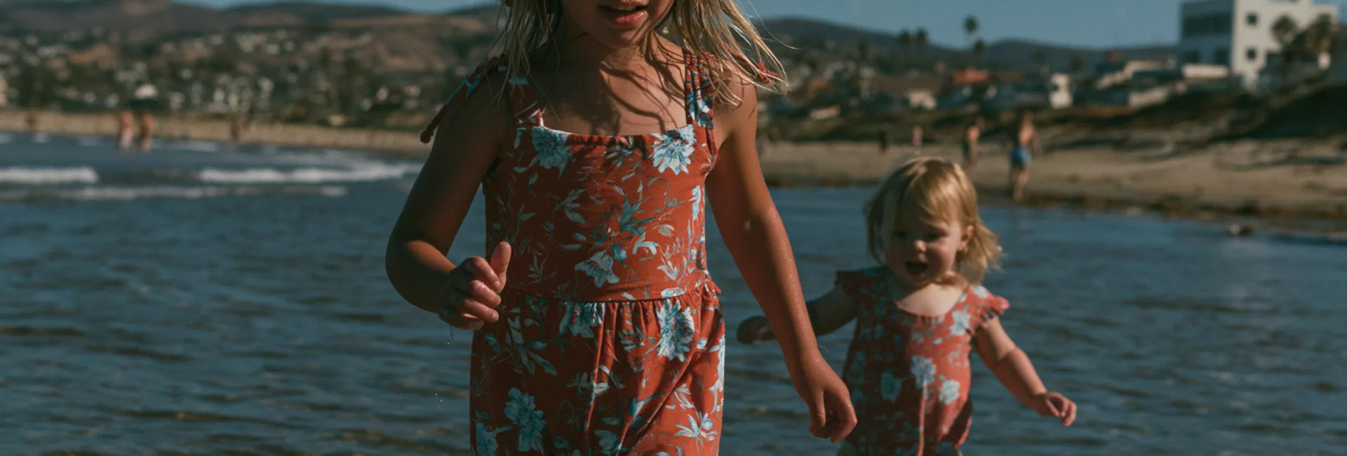 Deux jeunes enfants marchant seuls dans l'eau peu profonde au bord de la mer, illustrant l'importance de la surveillance pour prévenir les noyades.
