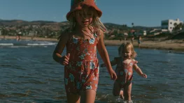 Deux jeunes enfants marchant seuls dans l'eau peu profonde au bord de la mer, illustrant l'importance de la surveillance pour prévenir les noyades.