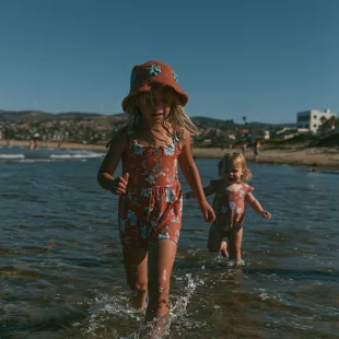 Deux jeunes enfants marchant seuls dans l'eau peu profonde au bord de la mer, illustrant l'importance de la surveillance pour prévenir les noyades.