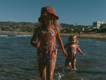 Deux jeunes enfants marchant seuls dans l'eau peu profonde au bord de la mer, illustrant l'importance de la surveillance pour prévenir les noyades.