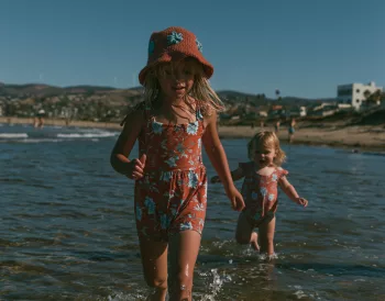 Deux jeunes enfants marchant seuls dans l'eau peu profonde au bord de la mer, illustrant l'importance de la surveillance pour prévenir les noyades.