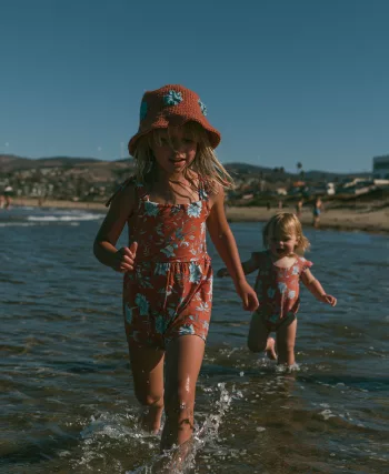 Deux jeunes enfants marchant seuls dans l'eau peu profonde au bord de la mer, illustrant l'importance de la surveillance pour prévenir les noyades.