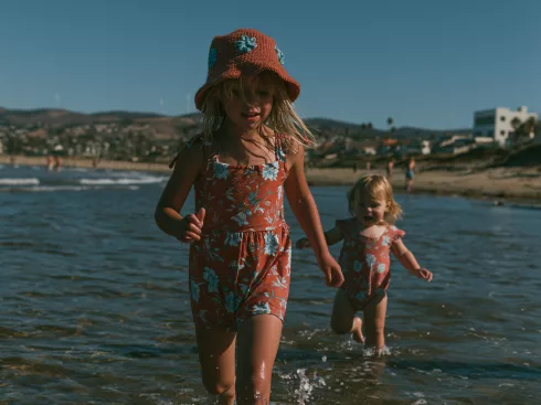 Deux jeunes enfants marchant seuls dans l'eau peu profonde au bord de la mer, illustrant l'importance de la surveillance pour prévenir les noyades.
