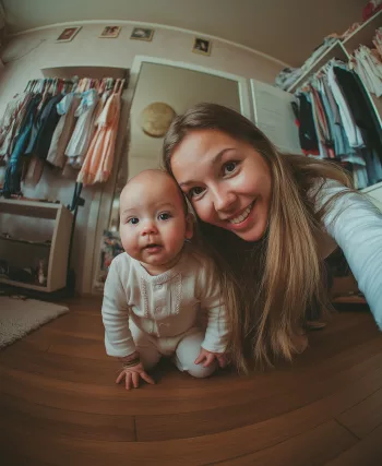Assistante maternelle souriante prenant un selfie avec un bébé, à son domicile