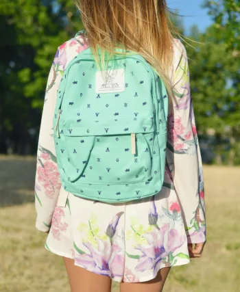 Enfant de dos portant un cartable turquoise dans un parc, image illustrant la rentrée scolaire et les dépenses liées aux fournitures. allocation de rentrée scolaire