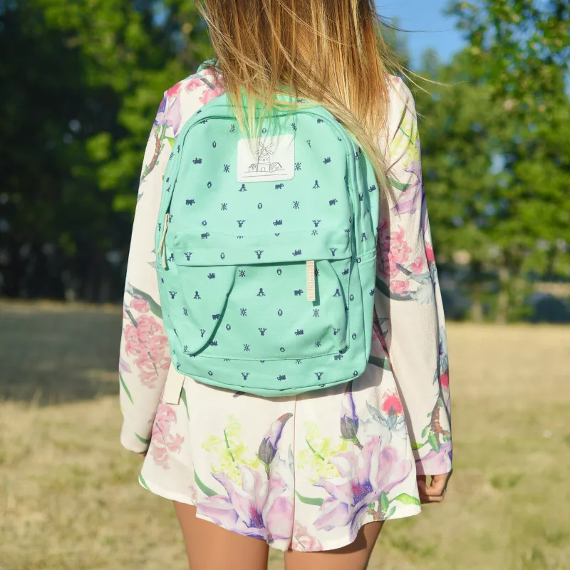 Enfant de dos portant un cartable turquoise dans un parc, image illustrant la rentrée scolaire et les dépenses liées aux fournitures. allocation de rentrée scolaire
