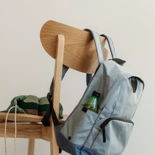 Rentrée scolaire 2026 Cartable gris accroché au dossier d'une chaise en bois, baskets posées sur l'assise, en fin de journée d'école