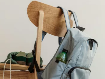 Rentrée scolaire 2026 Cartable gris accroché au dossier d'une chaise en bois, baskets posées sur l'assise, en fin de journée d'école
