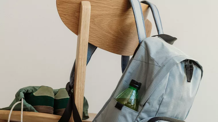 Rentrée scolaire 2026 Cartable gris accroché au dossier d'une chaise en bois, baskets posées sur l'assise, en fin de journée d'école